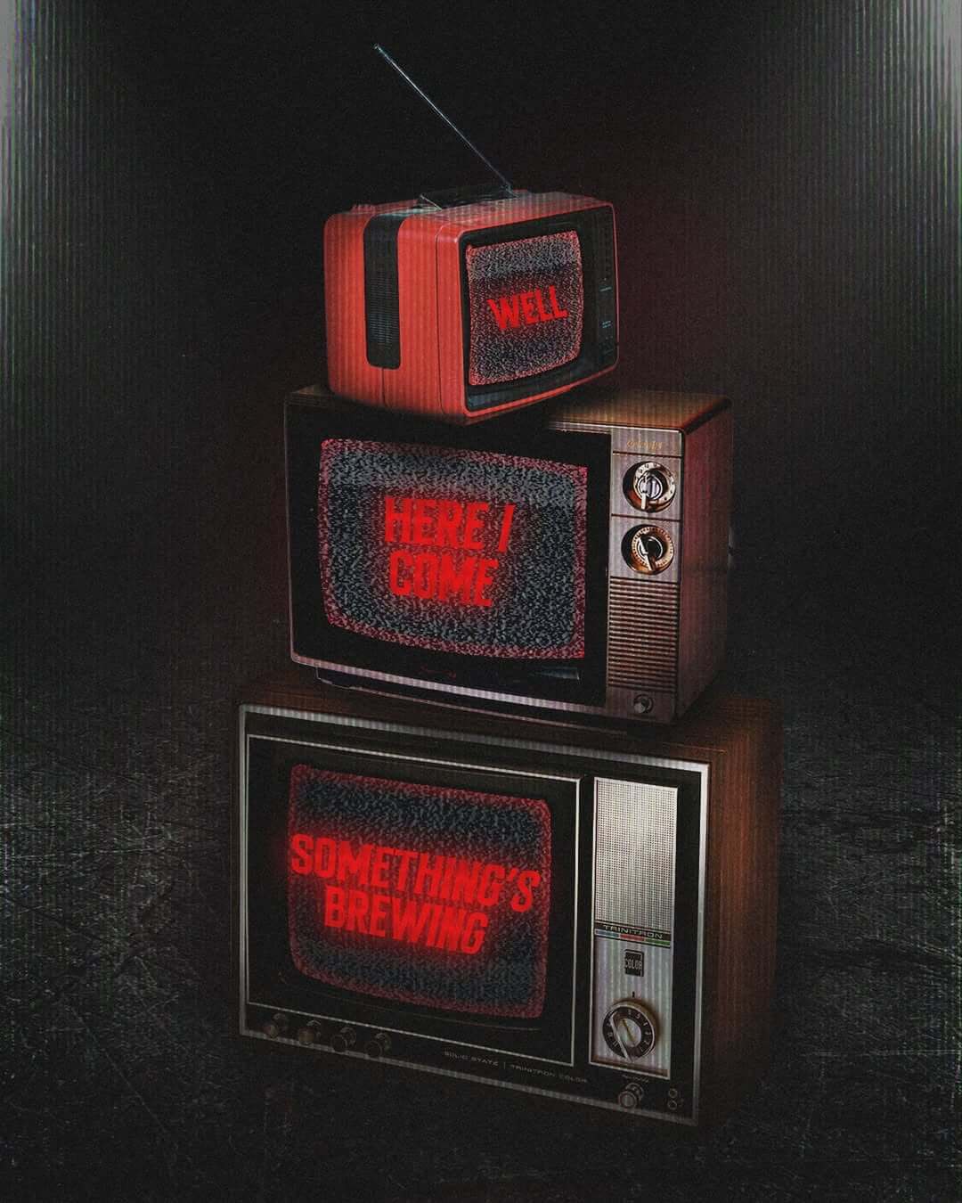 Tres televisores retro apilados, cada uno mostrando mensajes en rojo sobre estática: “WELL”, “HERE I COME” y “SOMETHING’S BREWING”, en un fondo oscuro.