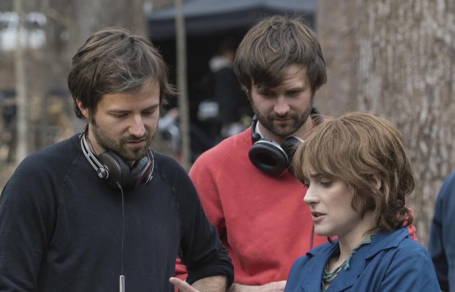 Los Duffer Brothers dejan Netflix: Matt y Ross Duffer revisan una escena junto a la actriz Winona Ryder durante el rodaje de Stranger Things, en un entorno boscoso con equipo técnico alrededor.