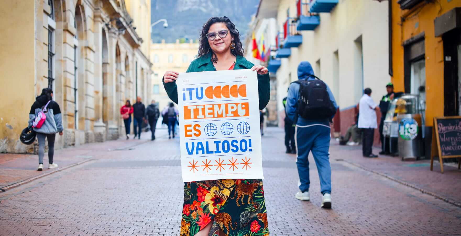 Mujer sostiene un cartel en el centro de Bogotá con el mensaje “Tu tiempo es valioso”, como parte del reconocimiento de Bogotá Capital Mundial del Tiempo