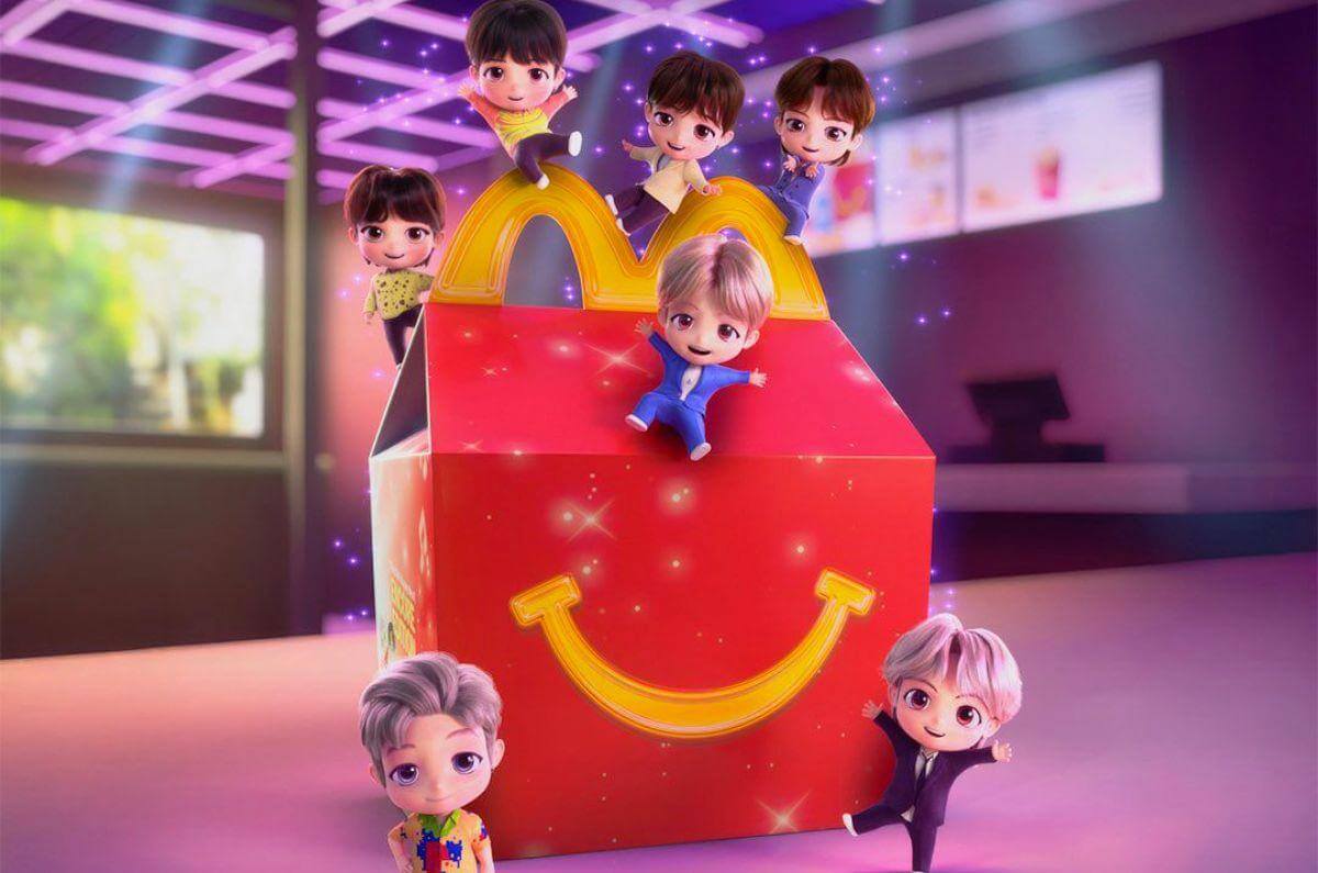 Los siete personajes TinyTAN de BTS alrededor de una Cajita Feliz de McDonald’s, mostrando sus versiones animadas con outfits icónicos