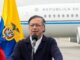 El presidente Gustavo Petro ofrece una alocución frente a un micrófono, con la bandera de Colombia a su lado y un avión oficial con la inscripción “República de Colombia” de fondo, en el contexto de la descertificación de Colombia