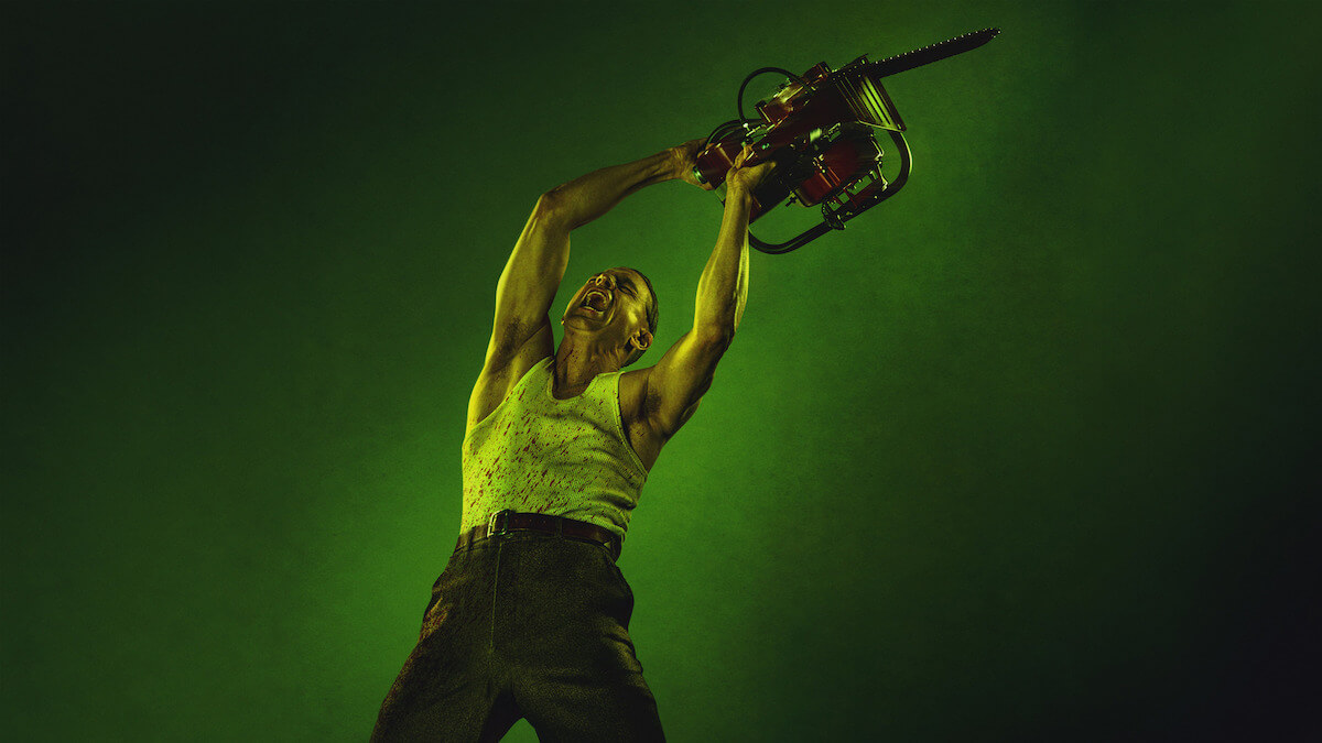 El actor Charlie Hunnam en Monster: la historia de Ed Gein, levantando una motosierra sobre un fondo verde, en una imagen promocional de Netflix