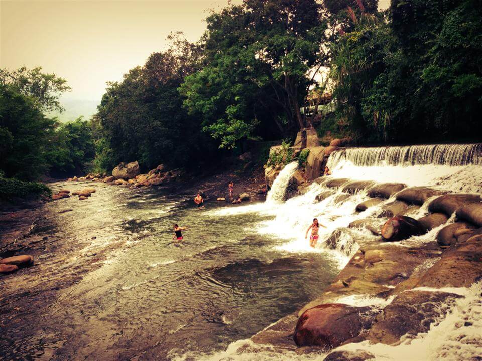 La Bocatoma de Bagazal en Villeta, con caídas de agua artificial entre rocas y árboles, donde visitantes disfrutan del paisaje y el río