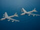 Dos bombarderos B-52H de la Fuerza Aérea de Estados Unidos sobrevuelan el mar Caribe en formación, vistos desde un dron, con líneas de radar visibles en el cielo. Representa las aeronaves más monitoreadas del mundo