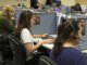 Agentes de un centro de llamadas trabajando frente a computadores, representando las comunicaciones comerciales no autorizadas mencionadas en la sanción de la SIC a Movistar