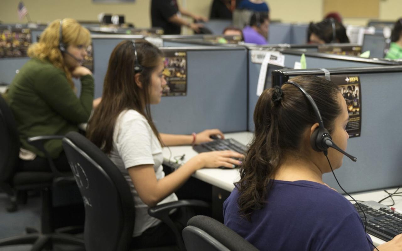 Agentes de un centro de llamadas trabajando frente a computadores, representando las comunicaciones comerciales no autorizadas mencionadas en la sanción de la SIC a Movistar
