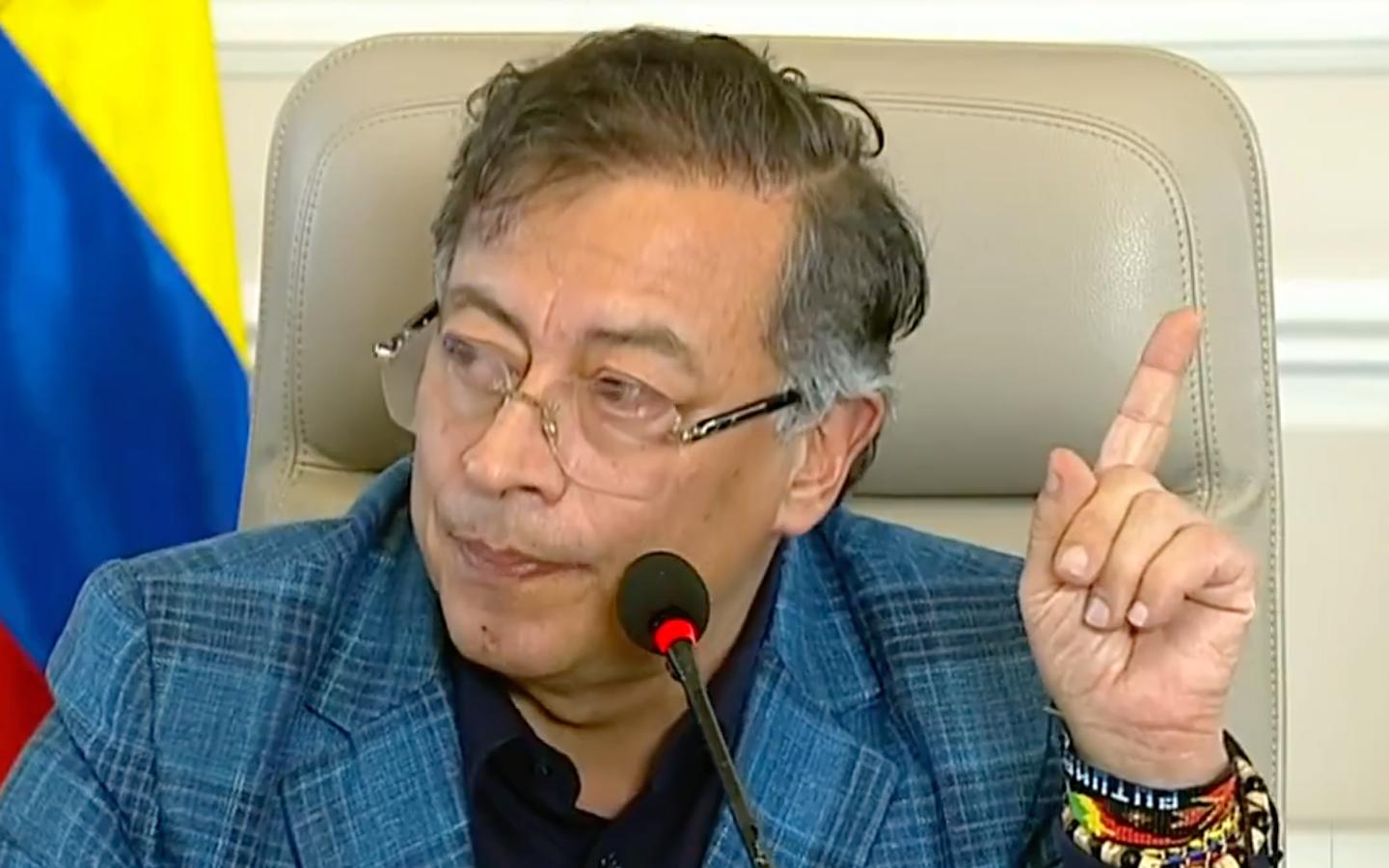 Primer plano del presidente Gustavo Petro durante una conferencia de prensa, con gesto serio y dedo levantado mientras hace una declaración; al fondo se observan los colores de la bandera de Colombia — intervención de Trump en Colombia