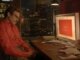 Escena de una película en la que un hombre observa la pantalla de su computadora con una luz cálida y reflexiva, representando la relación emocional entre humanos e inteligencia artificial en el contexto del contenido para adultos en ChatGPT