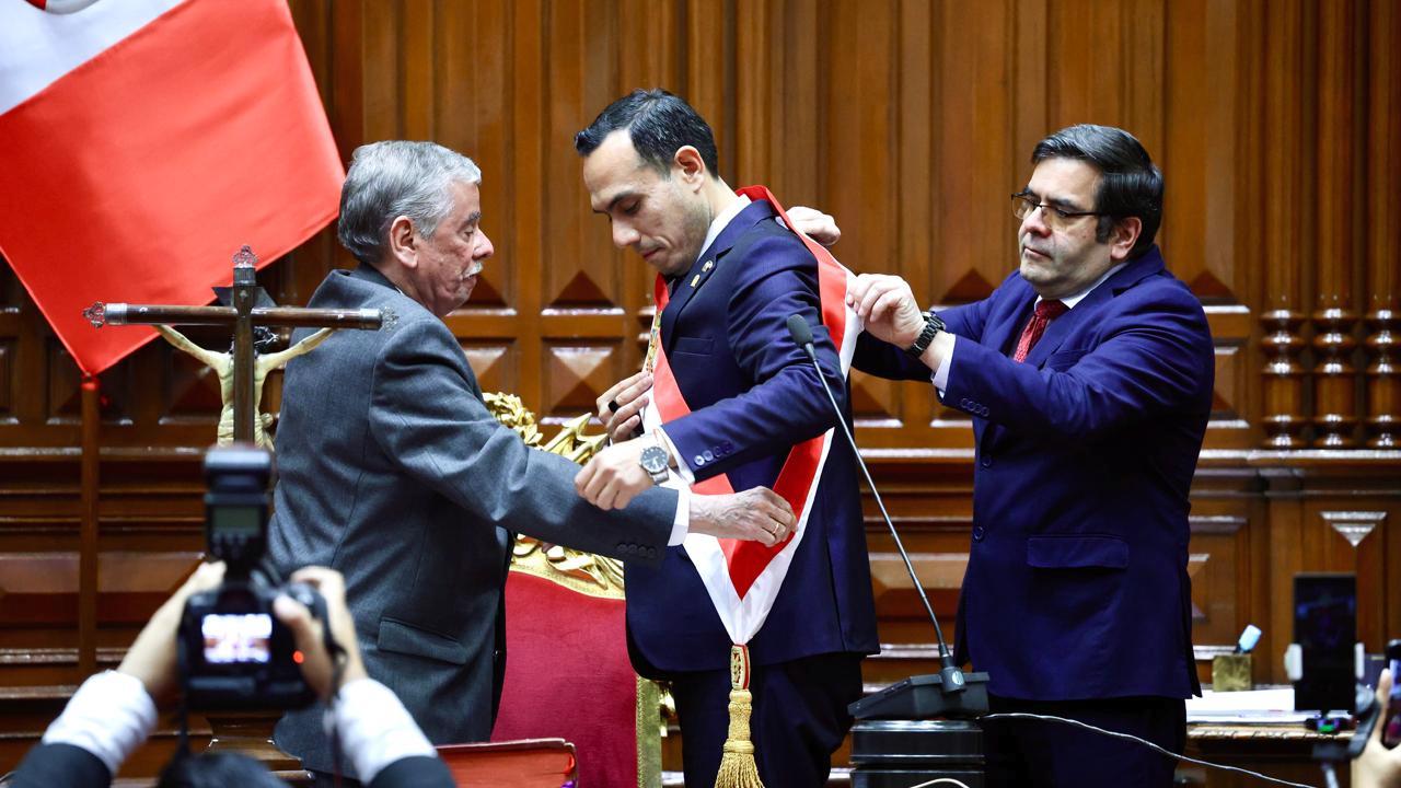 José Jerí Oré, nuevo presidente del Perú, recibe la banda presidencial durante su juramentación en el Congreso de la República, acompañado por funcionarios y frente a la bandera nacional