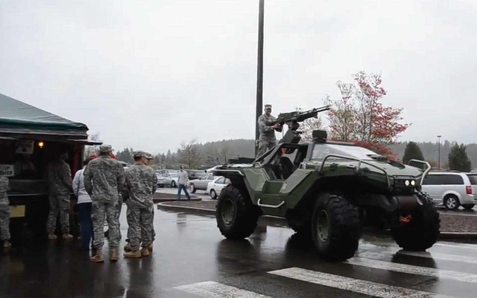 Soldados observan un vehículo militar inspirado en el Warthog de Halo durante una exhibición en un estacionamiento, en alusión simbólica al fin de la guerra de consolas