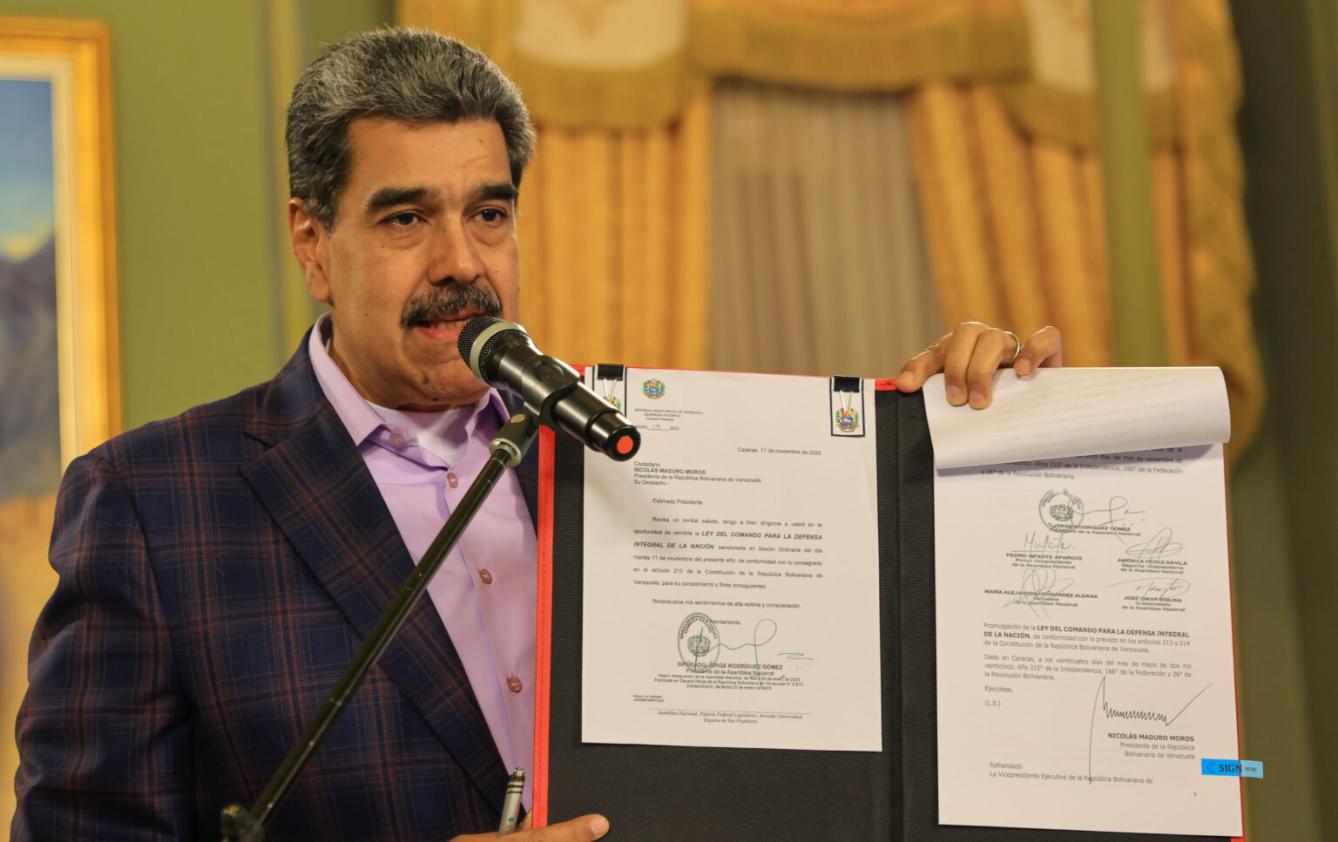 El presidente Nicolás Maduro sostiene y muestra el documento oficial de promulgación de la Ley del Comando para la Defensa Integral de la Nación, que establece el ejército de civiles y militares en Venezuela para reforzar la defensa nacional