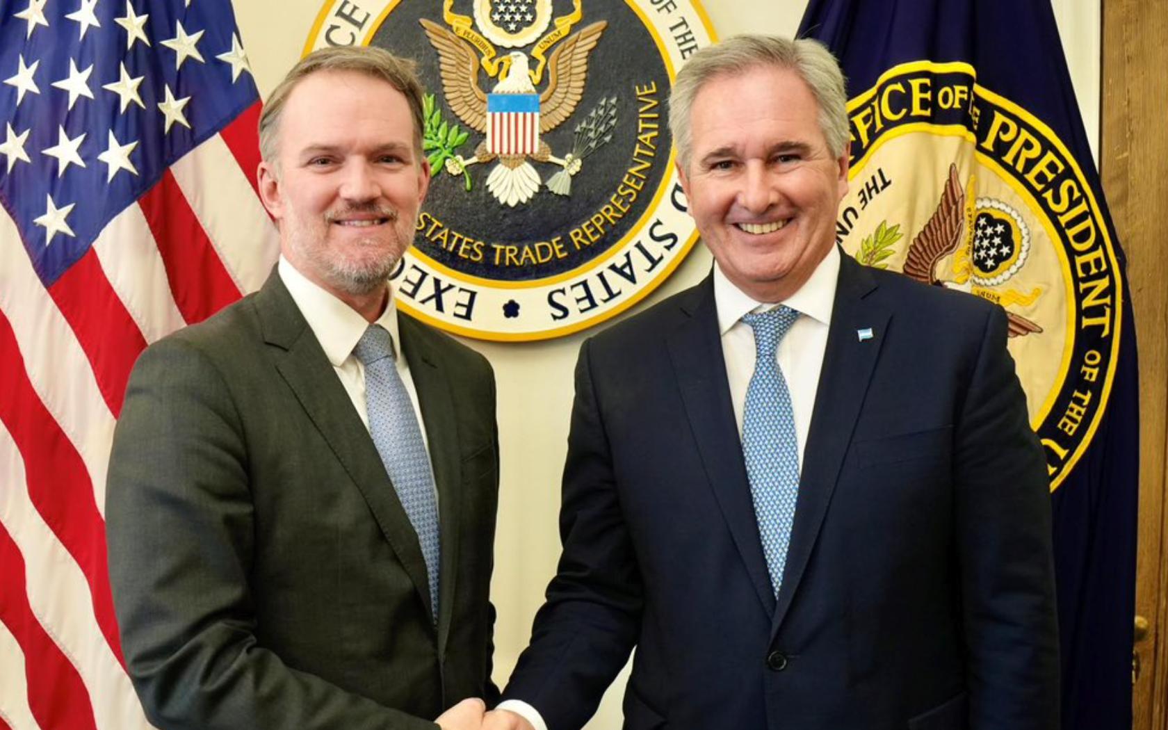 Pablo Quirno y Jamieson Greer estrechan las manos frente a emblemas oficiales en Washington, en el contexto del Acuerdo entre Estados Unidos y Argentina