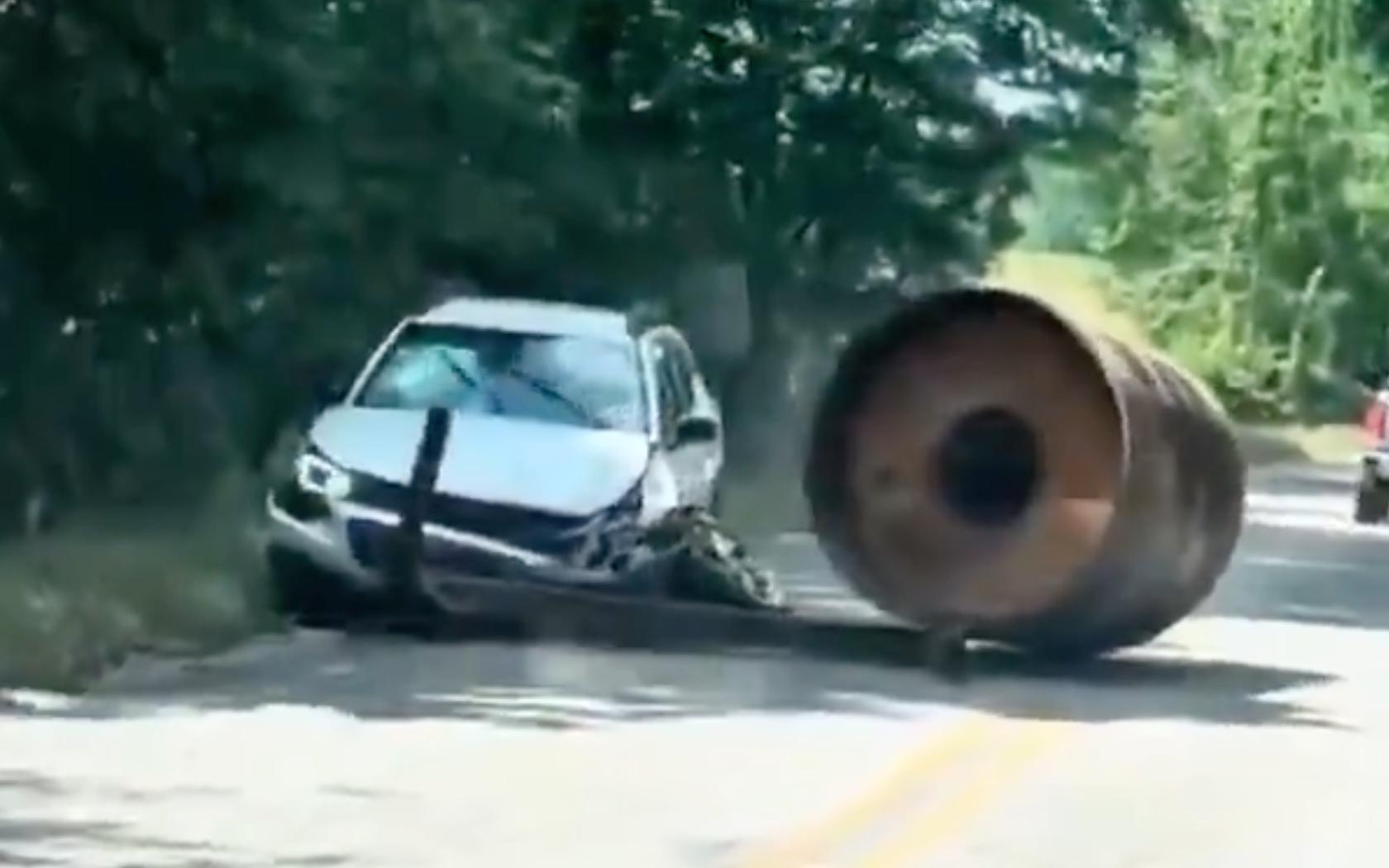 Momento del choque en el que un tambor de aplanadora aplastó un vehículo; se ve el carro blanco destruido al costado de la vía y el tambor metálico detenido frente a él sobre la carretera