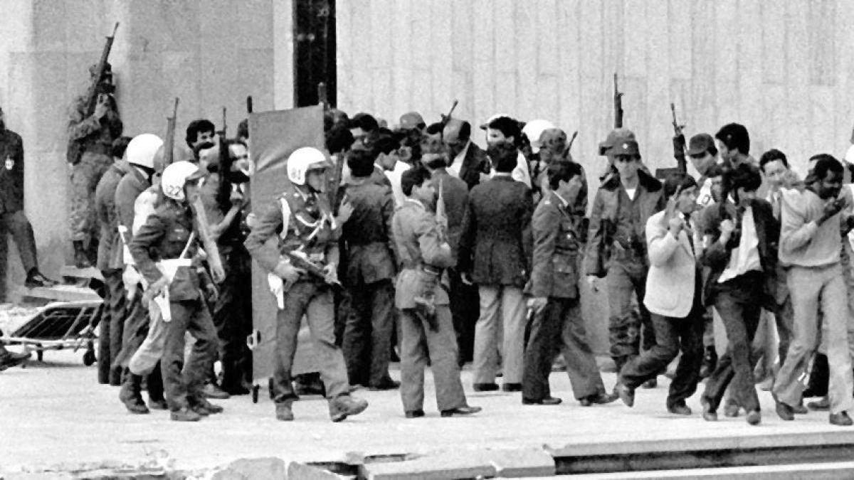 Militares escoltan a un grupo de civiles que salen del Palacio de Justicia durante la retoma de 1985, en medio del caos y la incertidumbre sobre los desaparecidos del Palacio de Justicia