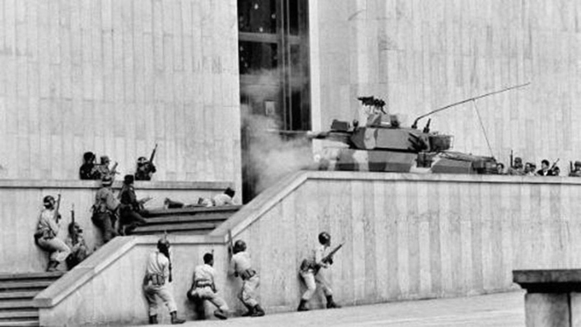 Soldados y un tanque del Ejército avanzan por las escaleras del Palacio de Justicia durante la toma de 1985, en medio del fuego cruzado y la confusión, un momento clave para entender la duración de la toma del Palacio de Justicia