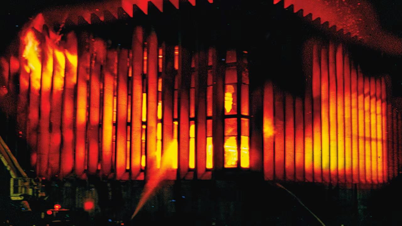 Fachada del Palacio de Justicia envuelta en llamas durante el asalto de 1985, con columnas iluminadas por el fuego que simboliza el incendio del Palacio de Justicia y la pérdida de archivos judiciales