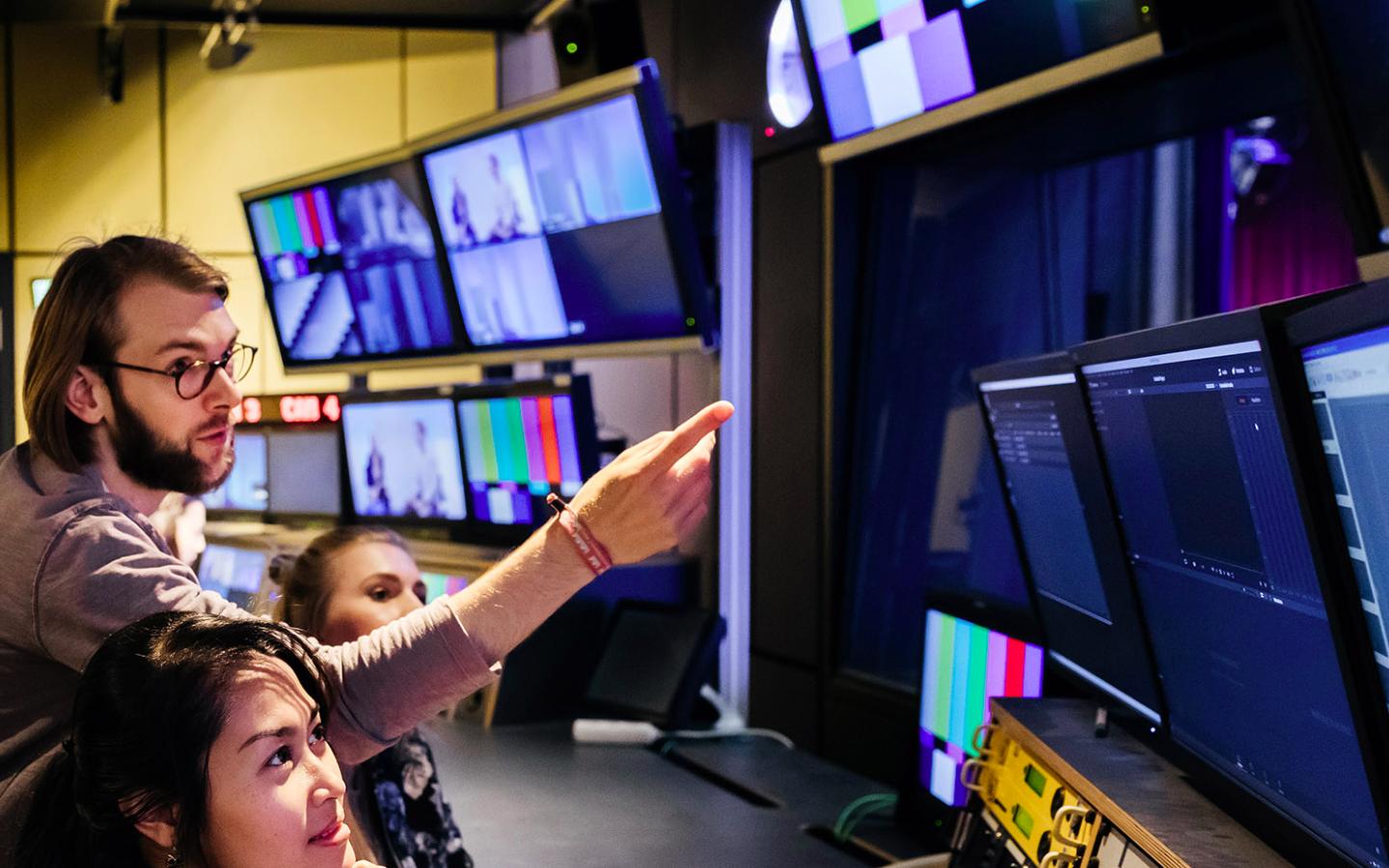 Técnicos trabajando frente a múltiples pantallas en una sala de control audiovisual, ilustrando el rol tecnológico detrás de la alianza entre Atos y la CONMEBOL