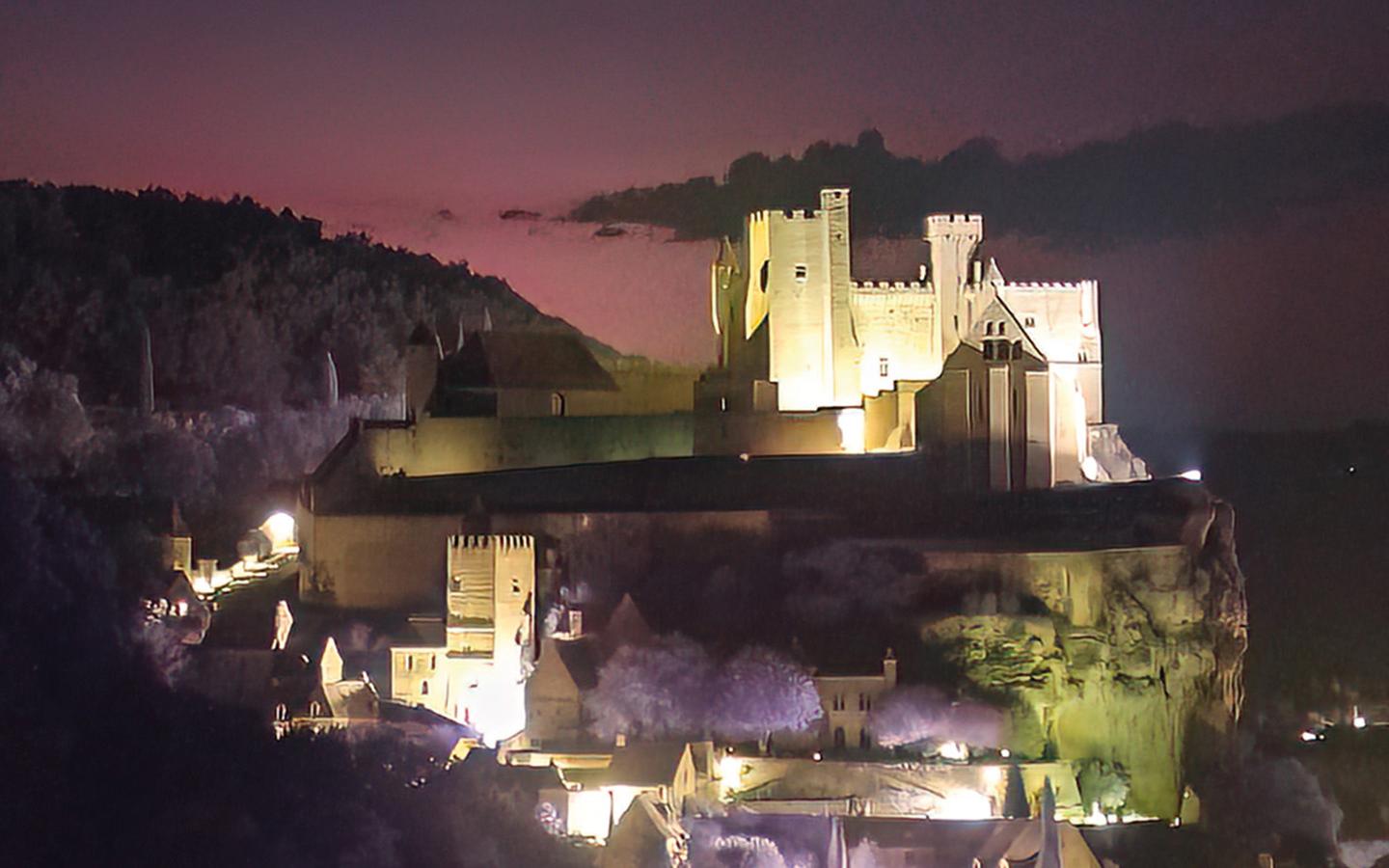 Castillo medieval de Beynac iluminado durante la noche, visto sobre una colina en Francia, bajo un cielo oscuro donde se registró la aparición de duendes rojos durante una tormenta eléctrica
