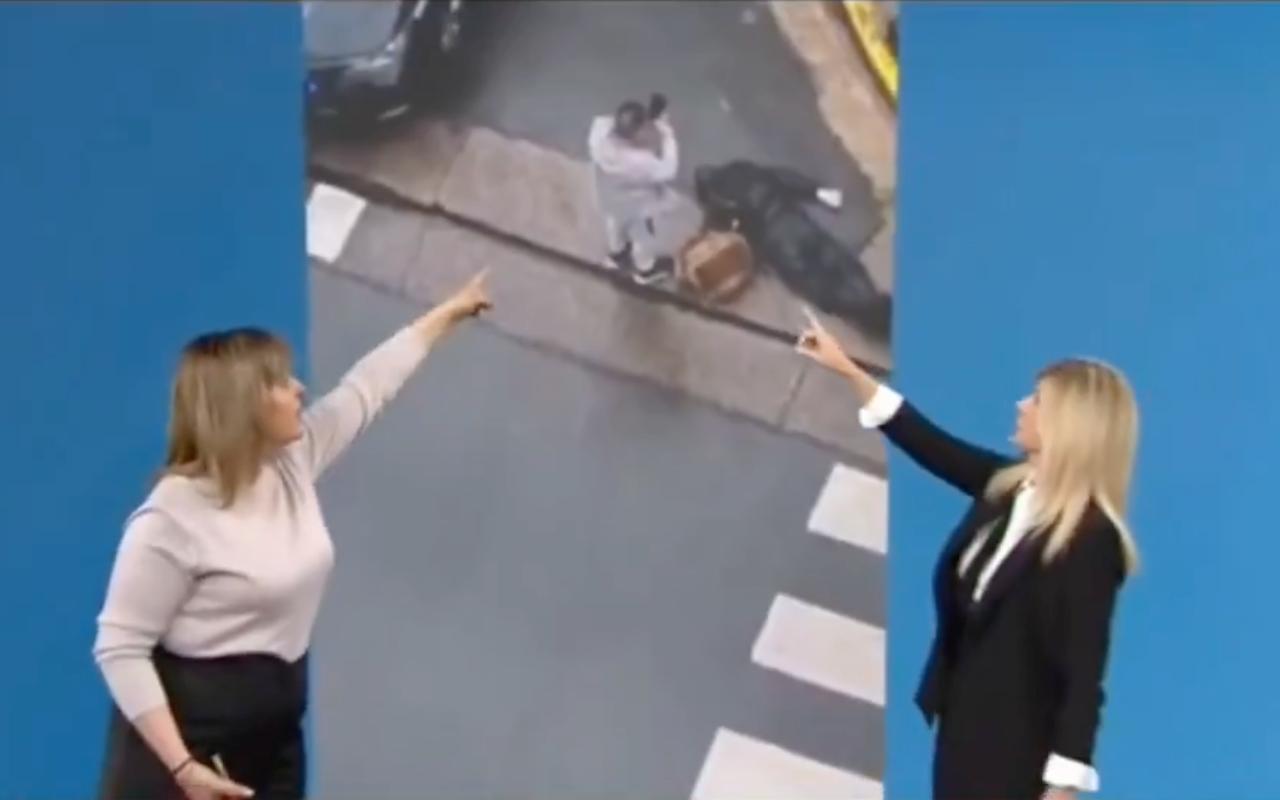 Dos presentadoras en estudio señalan una pantalla gigante donde se ve una escena callejera en perspectiva, con un hombre de pie y, a su lado, el cuerpo del fallecido con un vehículo parcialmente fuera de cuadro
