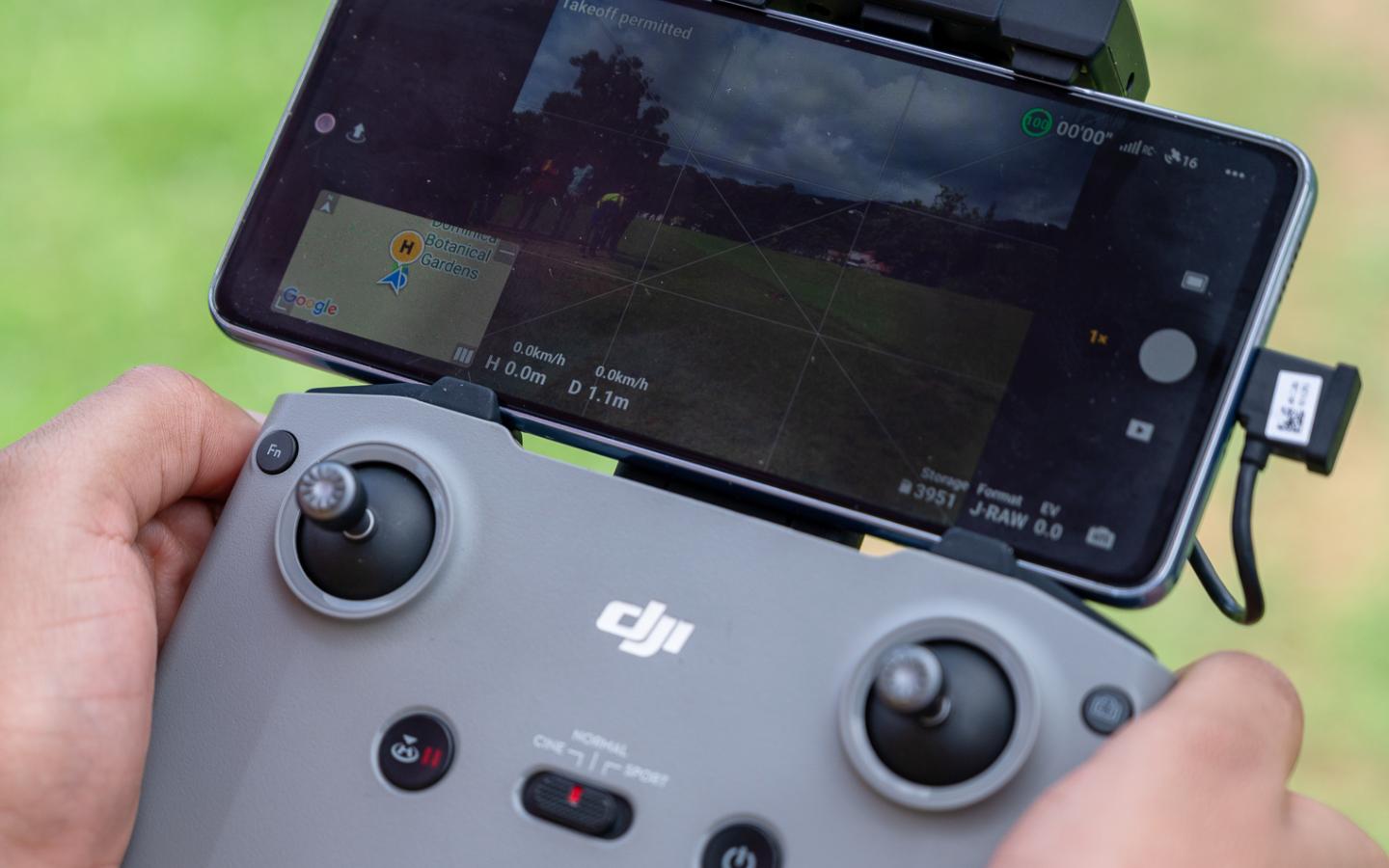 Primer plano de un control remoto DJI operado por un instructor mientras en la pantalla del dispositivo se observa la vista en vivo de un dron durante una capacitación apoyada por UNESCO en el Caribe